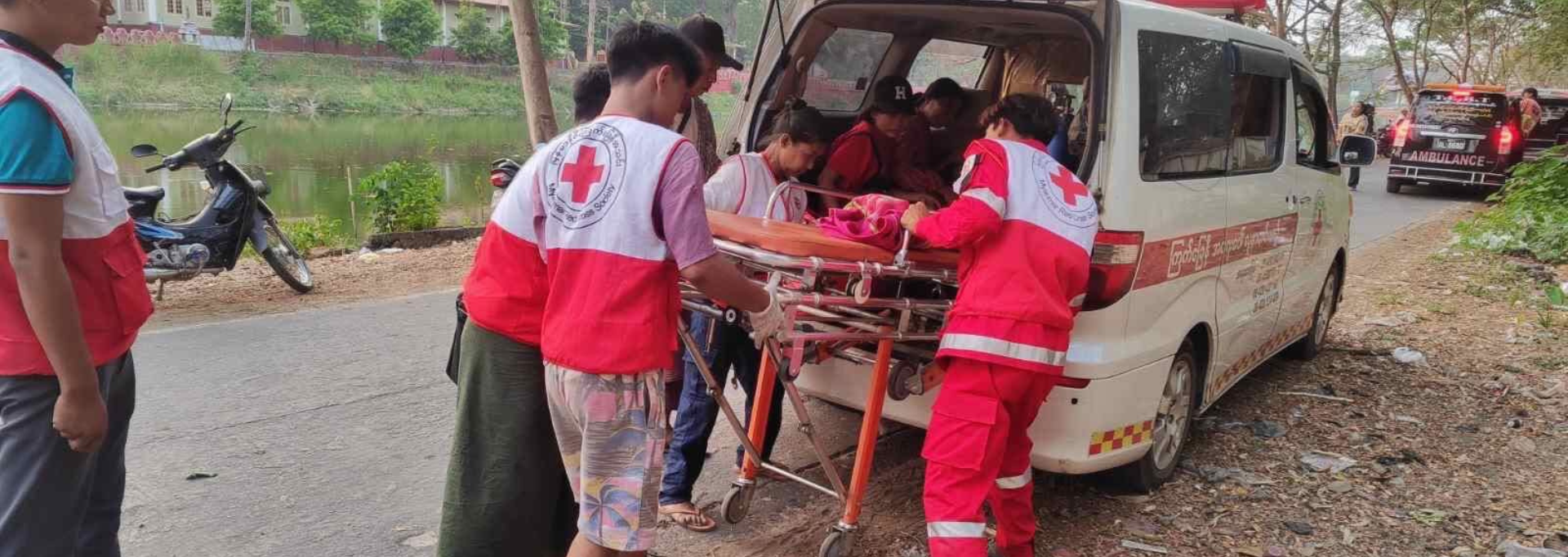 Red Cross aid worker feeding nutrient solution to a newborn baby.